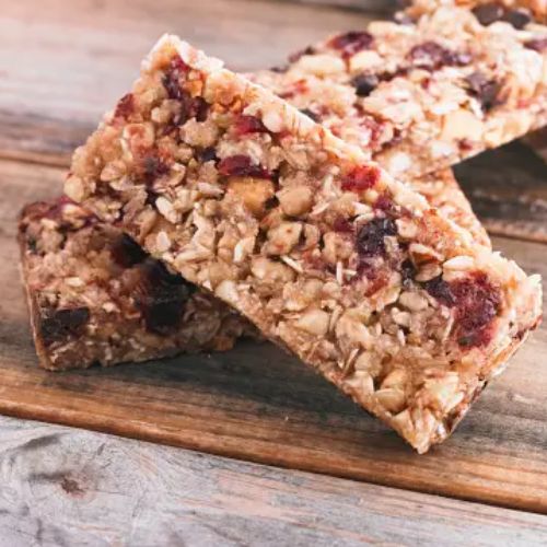 Two granola bars with oats and dried fruits placed on a wooden surface.