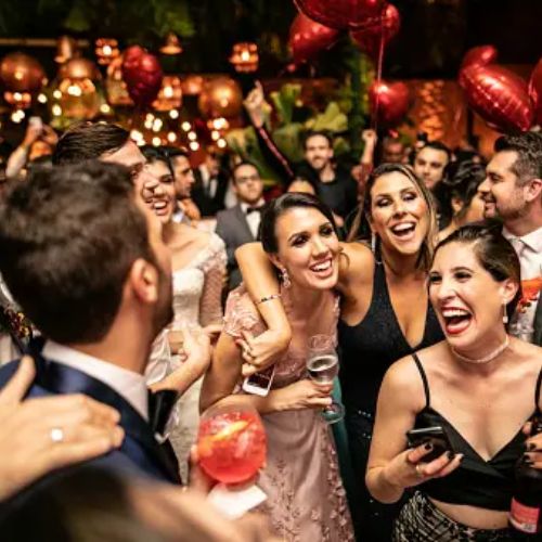 A lively group of people dressed formally and celebrating at a party with balloons and lights. Everyone is smiling and enjoying the event.