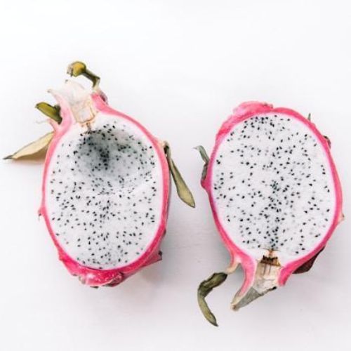 A close-up of a sliced dragon fruit, revealing its white flesh speckled with tiny black seeds. The two halves are placed on a white background.