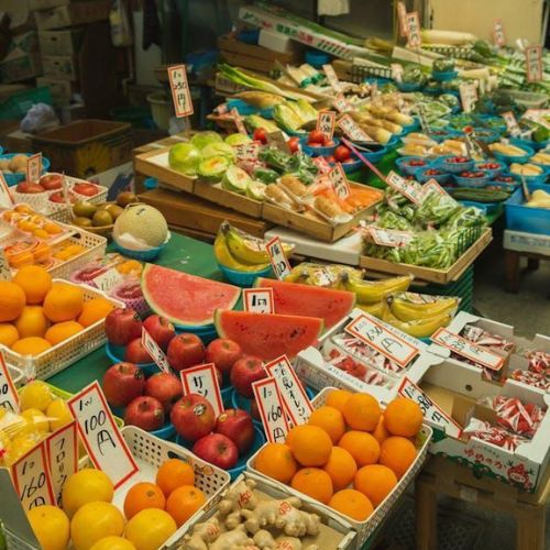 A market stall displaying a variety of fresh fruits and vegetables, with price tags on each item.