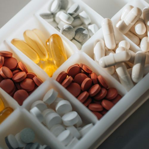 A pill organizer containing various types of pills and capsules in different compartments.