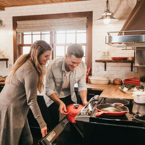 A couple actively engaged in cooking together in a warm kitchen, with focus on teamwork and family bonding.