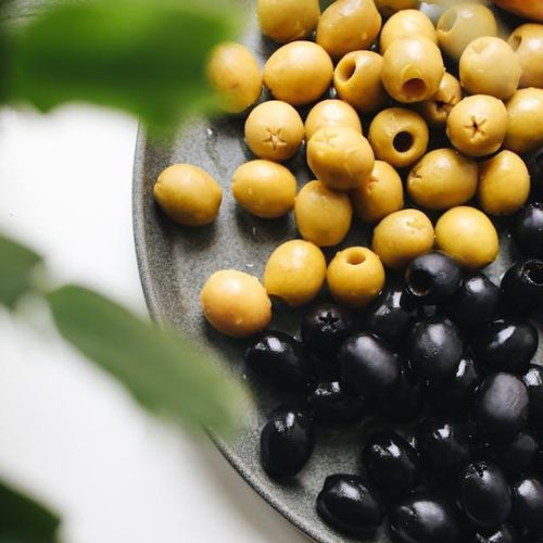 A round green plate with two distinct sections of olives, one with yellow-green olives and the other with black olives