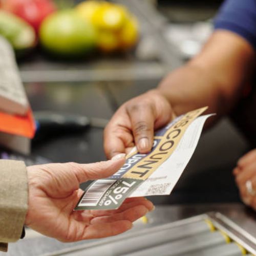 A close-up of a cashier's and customer's hands during a cash transaction, with a fifty euro note being handed over at a supermarket checkout.