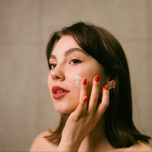 A woman applying cream to her face with a focus on her hands and her face