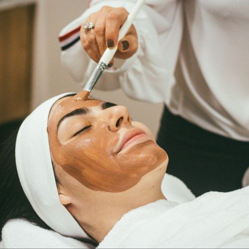 A woman relaxing with a chocolate facial mask being applied with a brush