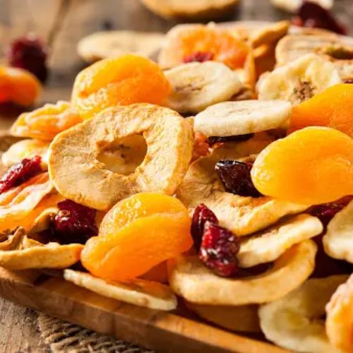 A wooden bowl filled with assorted dried fruits, including apricots, apples, and cranberries