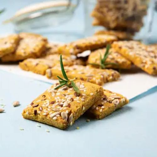 Seed crackers with herbs and seeds stacked on a light blue wooden surface