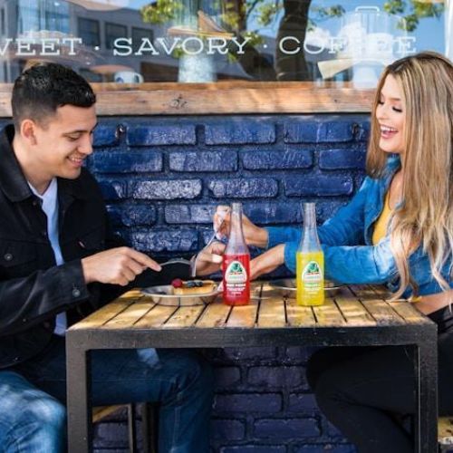 A young man and woman sitting at an outdoor café table, engaging in a lively conversation