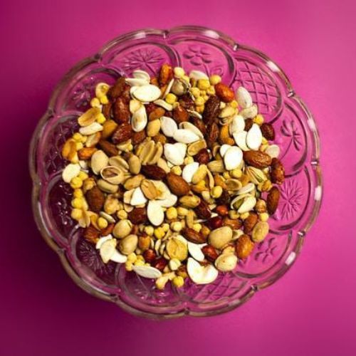 A clear glass bowl filled with an assortment of mixed nuts, including almonds, cashews, and peanuts