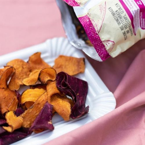 A serving of colorful vegetable chips, including orange, yellow, and purple varieties, on a white dish