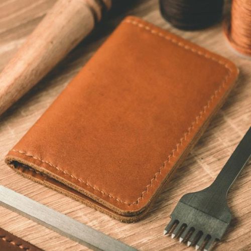 A top-down view of a handcrafted brown leather wallet on a wooden surface