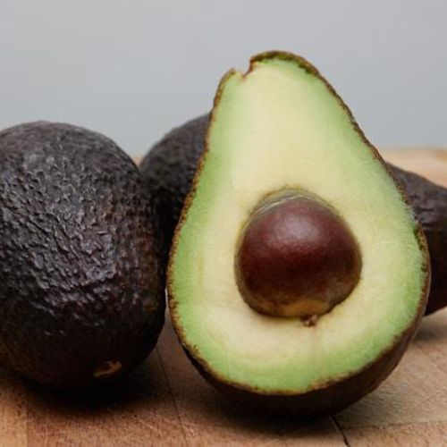 A close-up view of ripe avocados on a wooden surface