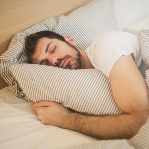 A man peacefully sleeping in bed, cuddling a pillow