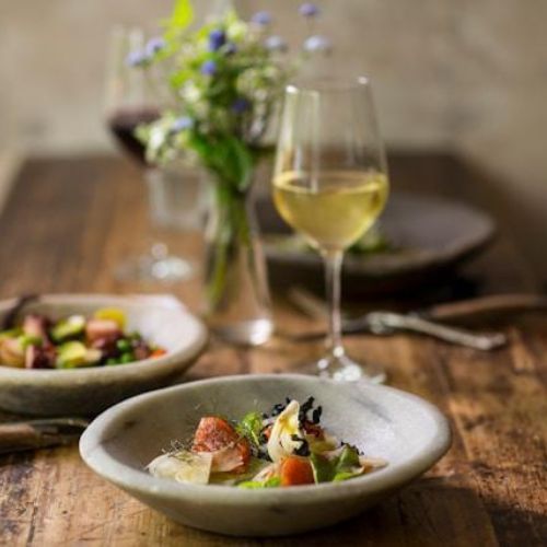 A beautifully set dining table with artisanal dishes and glasses of wine